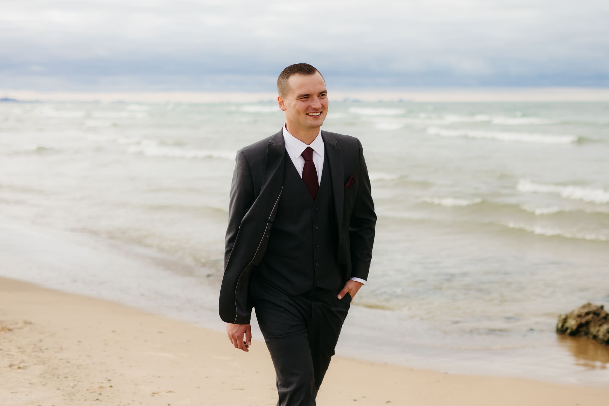 Bride and groom embrace and take couple portraits together along the beach of Lake Michigan during their Indiana Dunes National Park wedding.
