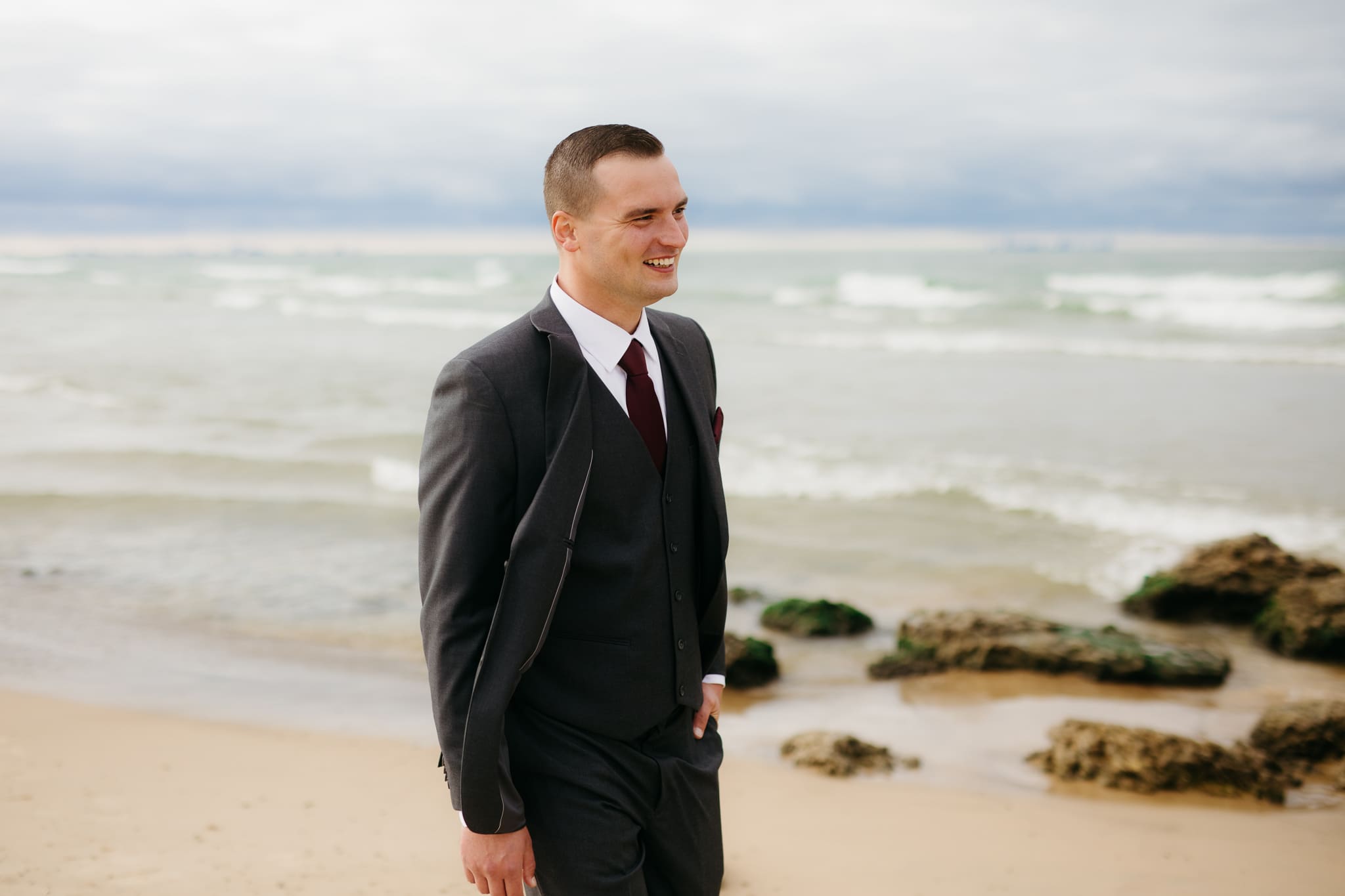 Bride and groom embrace and take couple portraits together along the beach of Lake Michigan during their Indiana Dunes National Park wedding.