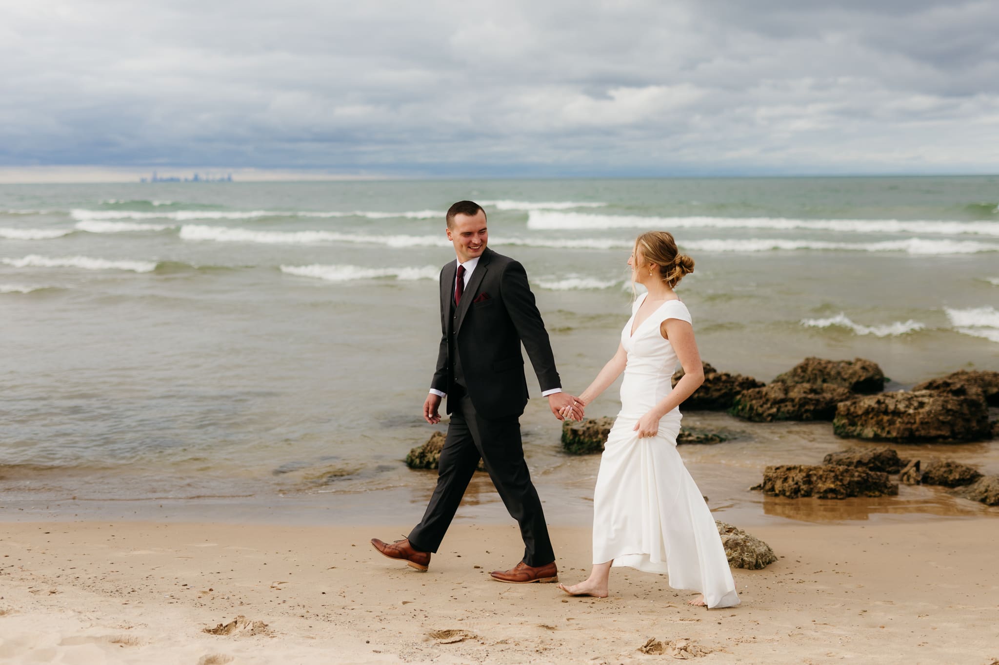 Bride and groom embrace and take couple portraits together along the beach of Lake Michigan during their Indiana Dunes National Park wedding.