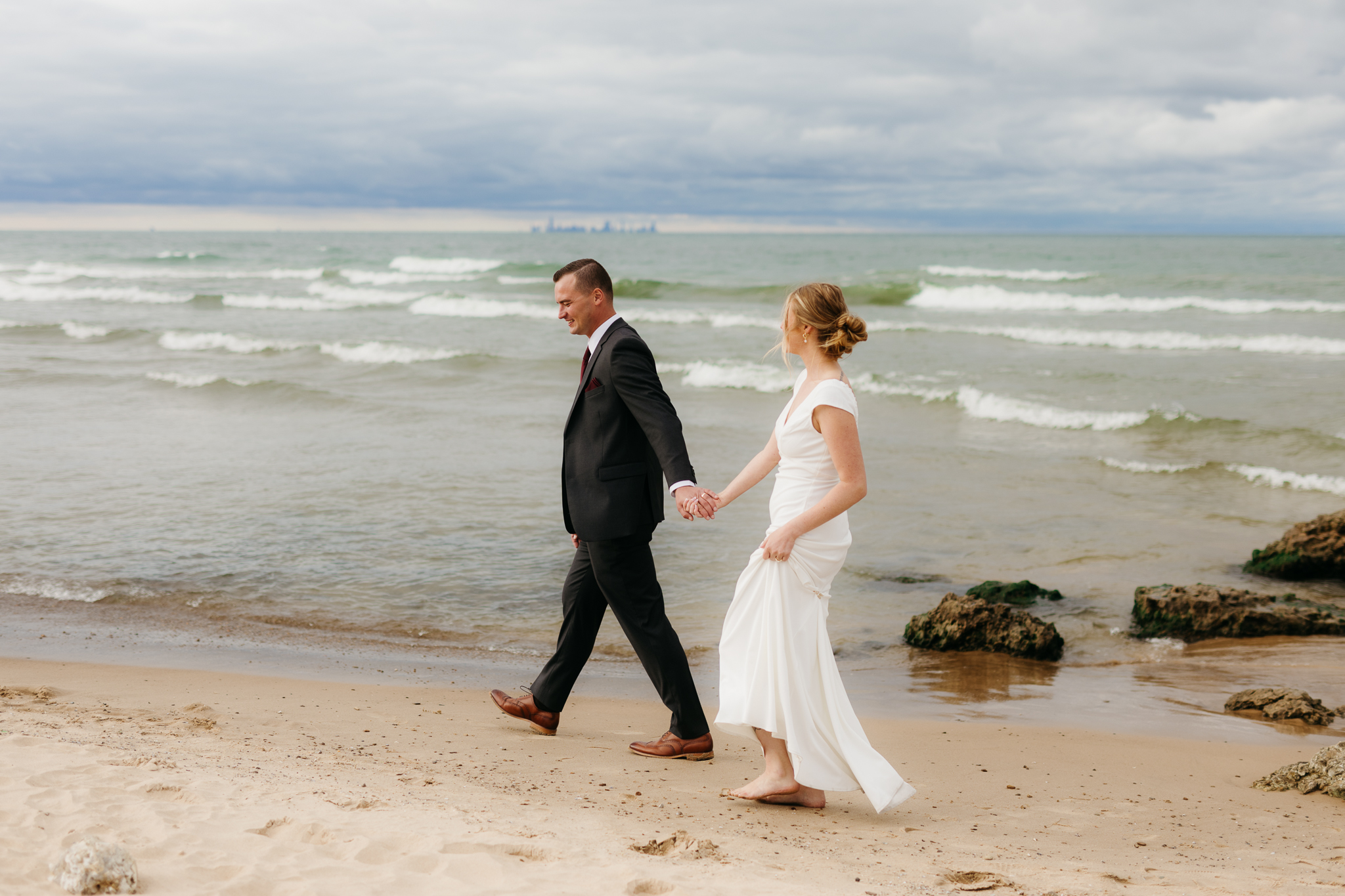Bride and groom embrace and take couple portraits together along the beach of Lake Michigan during their Indiana Dunes National Park wedding.