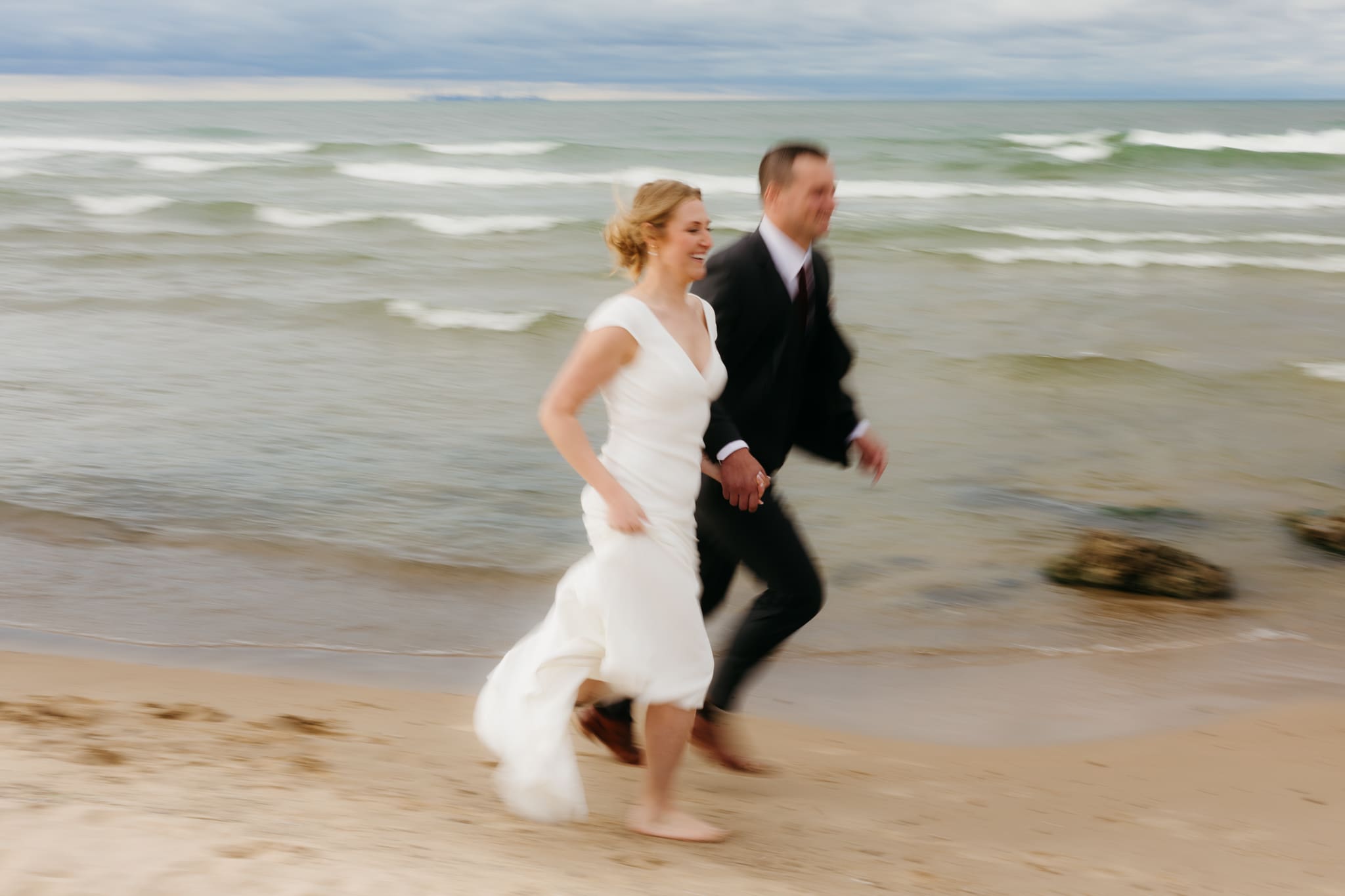 Bride and groom embrace and take couple portraits together along the beach of Lake Michigan during their Indiana Dunes National Park wedding.