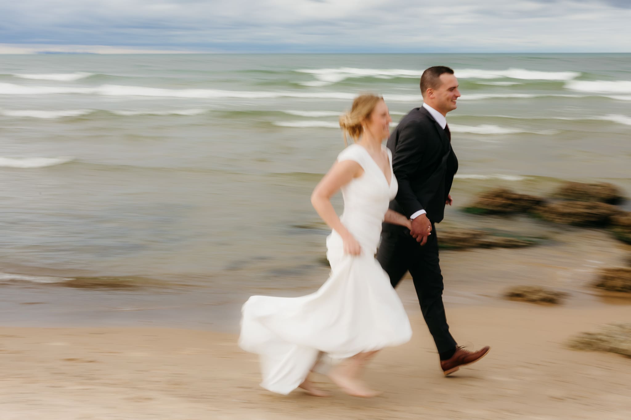 Bride and groom embrace and take couple portraits together along the beach of Lake Michigan during their Indiana Dunes National Park wedding.