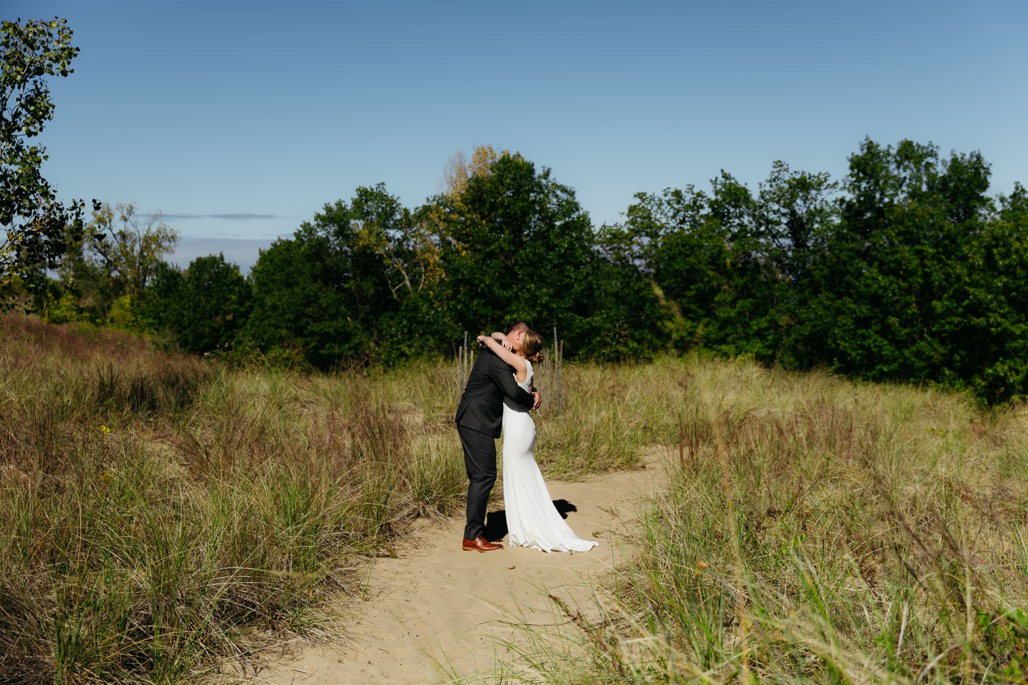 Bride and groom exchange private vows among the dunes of Indiana Dunes National Park, with dune grass swaying in the breeze.