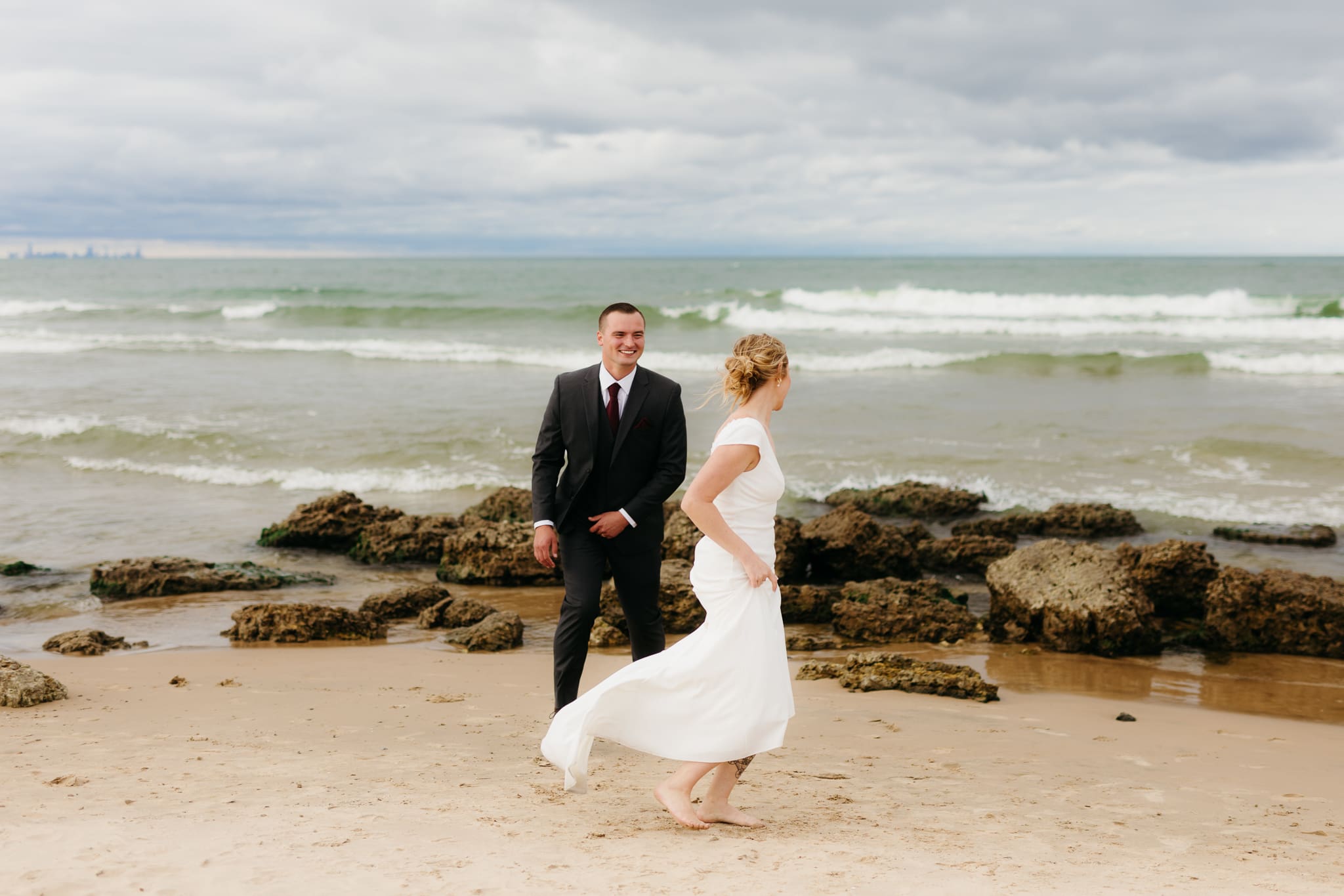 Bride and groom embrace and take couple portraits together along the beach of Lake Michigan during their Indiana Dunes National Park wedding.