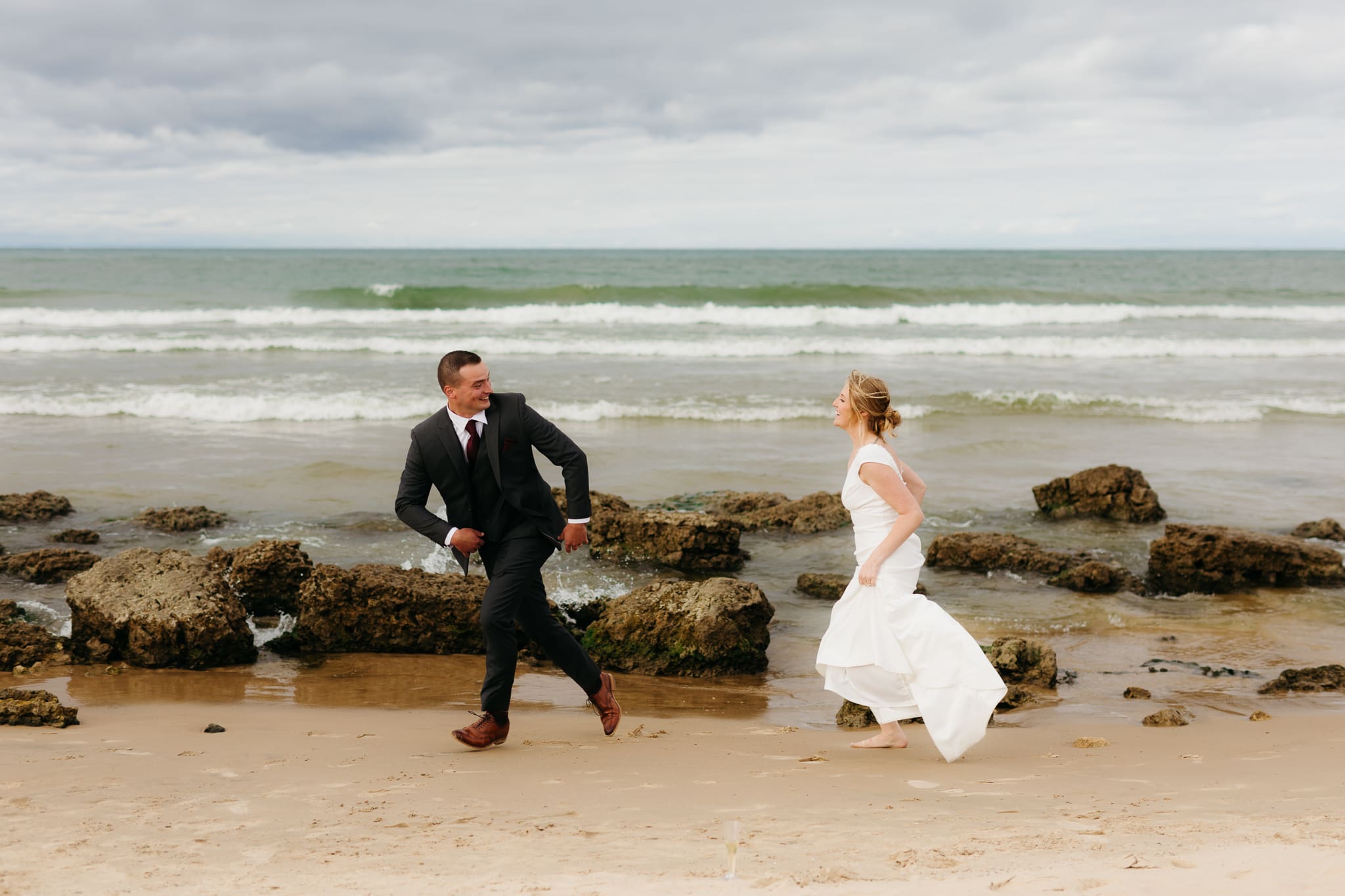 Bride and groom embrace and take couple portraits together along the beach of Lake Michigan during their Indiana Dunes National Park wedding.