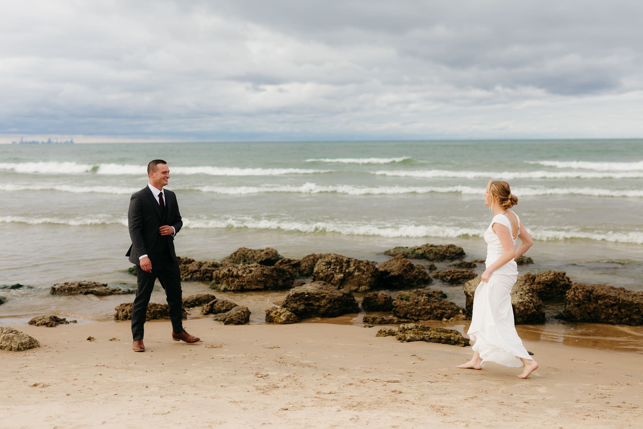 Bride and groom embrace and take couple portraits together along the beach of Lake Michigan during their Indiana Dunes National Park wedding.