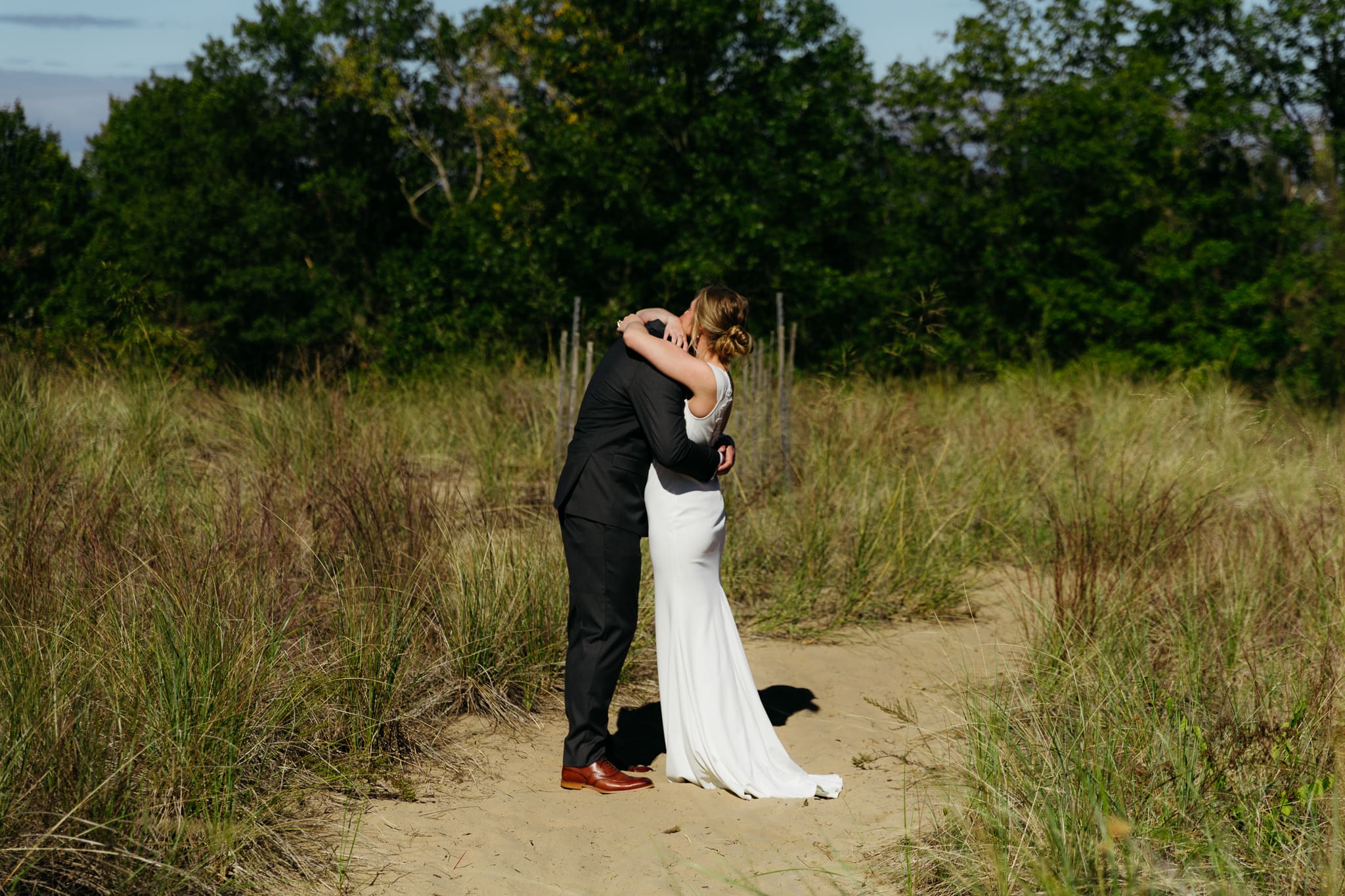 Bride and groom exchange private vows among the dunes of Indiana Dunes National Park, with dune grass swaying in the breeze.
