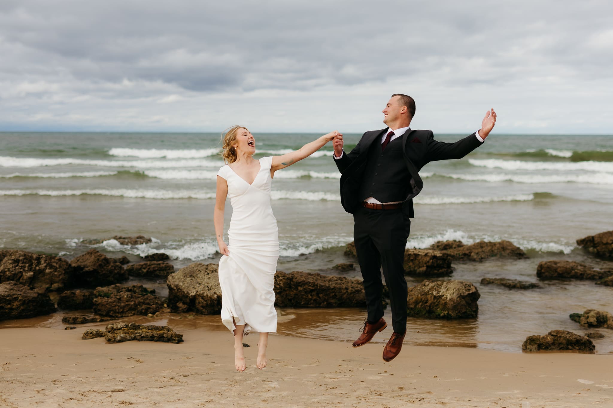 Bride and groom embrace and take couple portraits together along the beach of Lake Michigan during their Indiana Dunes National Park wedding.