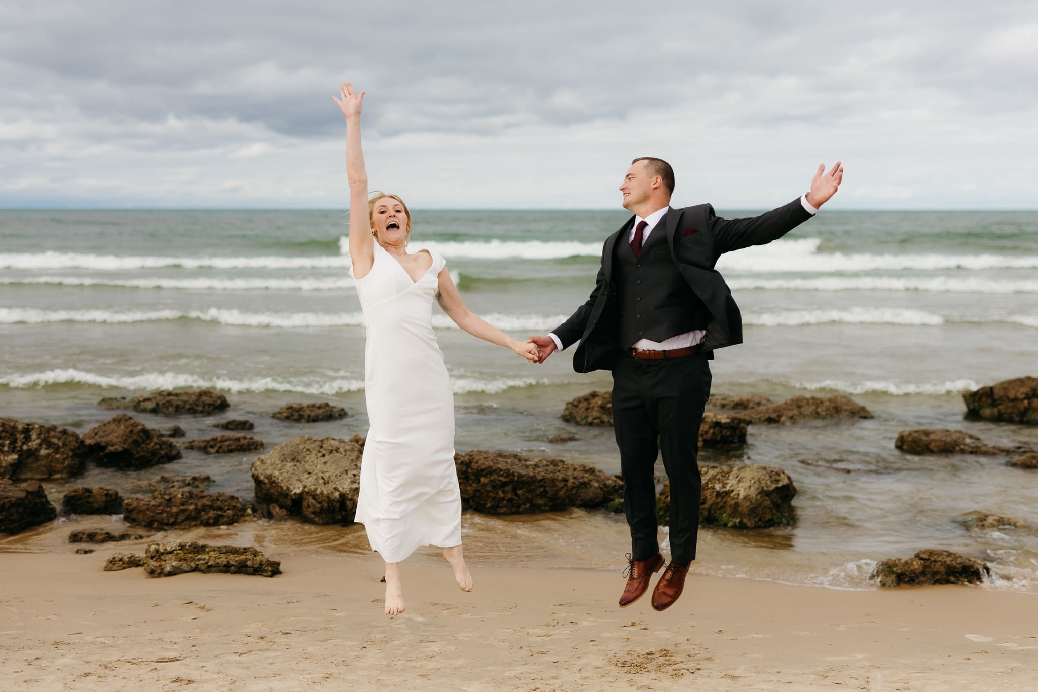 Bride and groom embrace and take couple portraits together along the beach of Lake Michigan during their Indiana Dunes National Park wedding.