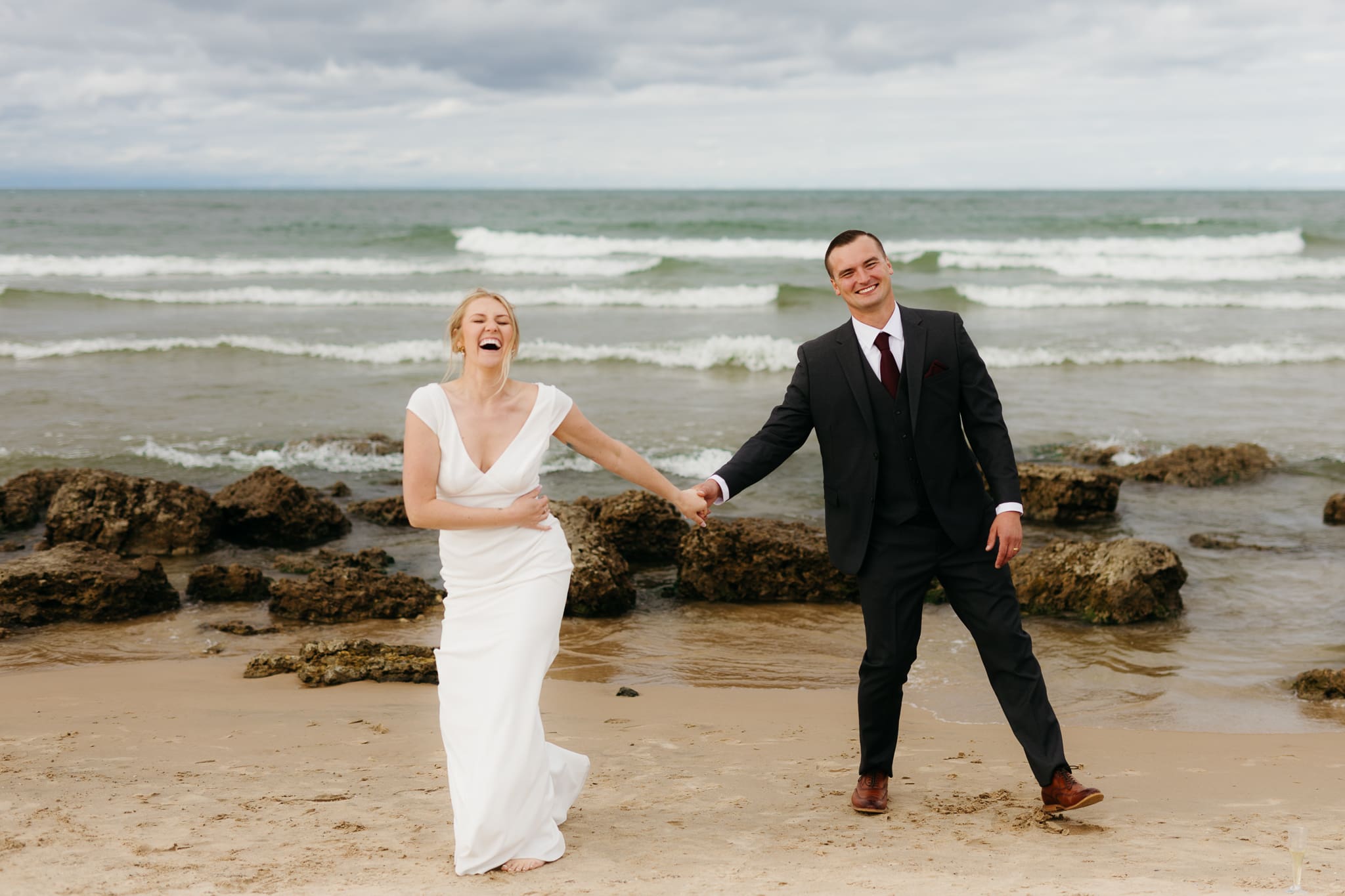 Bride and groom embrace and take couple portraits together along the beach of Lake Michigan during their Indiana Dunes National Park wedding.