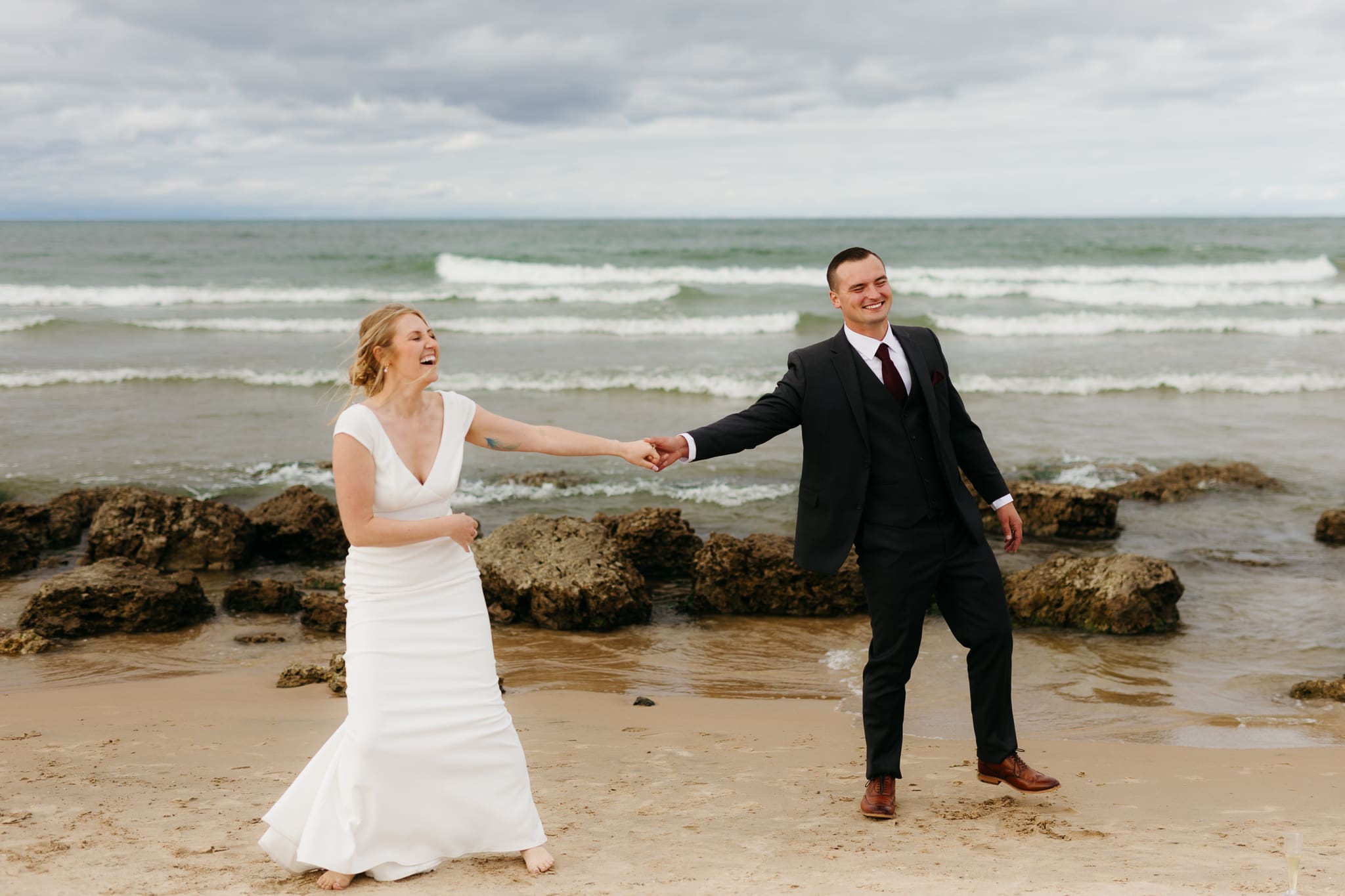 Bride and groom embrace and take couple portraits together along the beach of Lake Michigan during their Indiana Dunes National Park wedding.