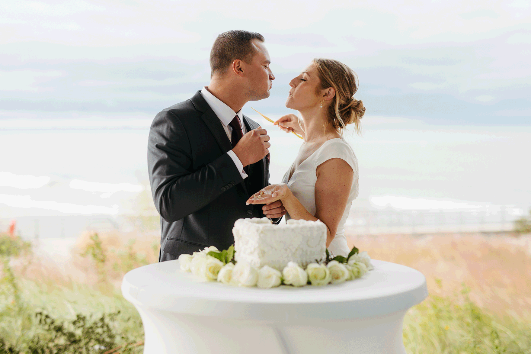 Bride and groom cut cake during their outdoor wedding reception at Indiana Dunes National Park