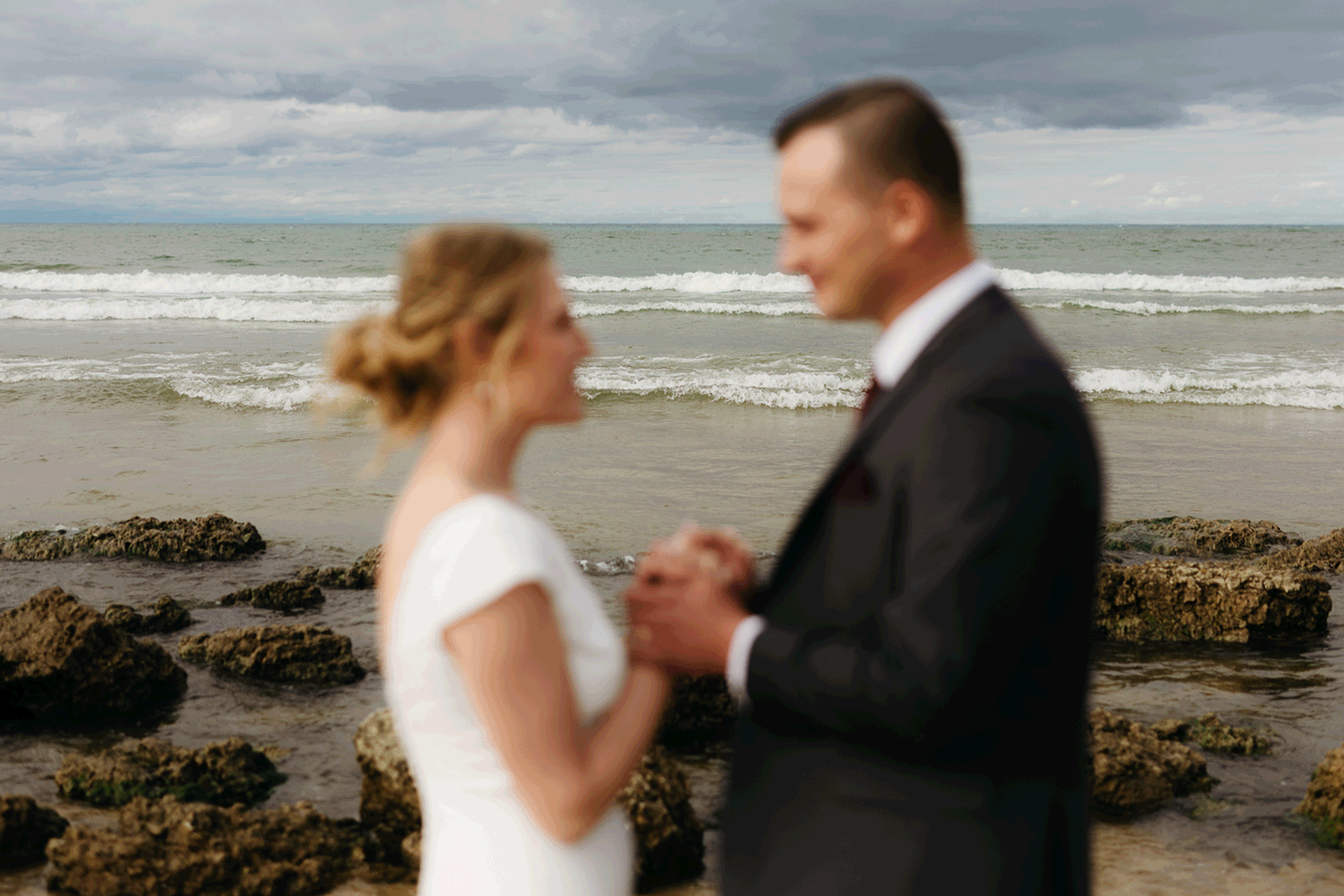 Bride and groom embrace and take couple portraits together along the beach of Lake Michigan during their Indiana Dunes National Park wedding.