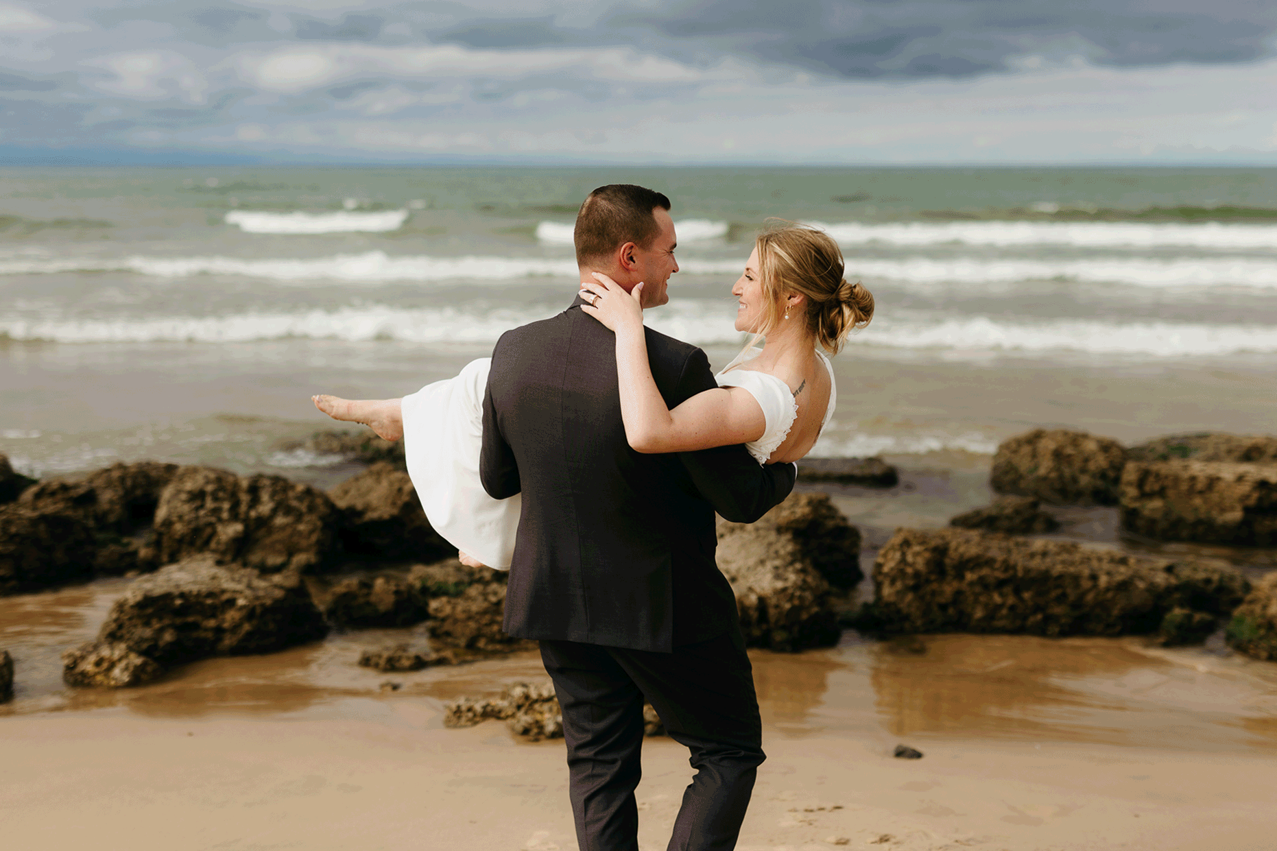 Bride and groom embrace and take couple portraits together along the beach of Lake Michigan during their Indiana Dunes National Park wedding.