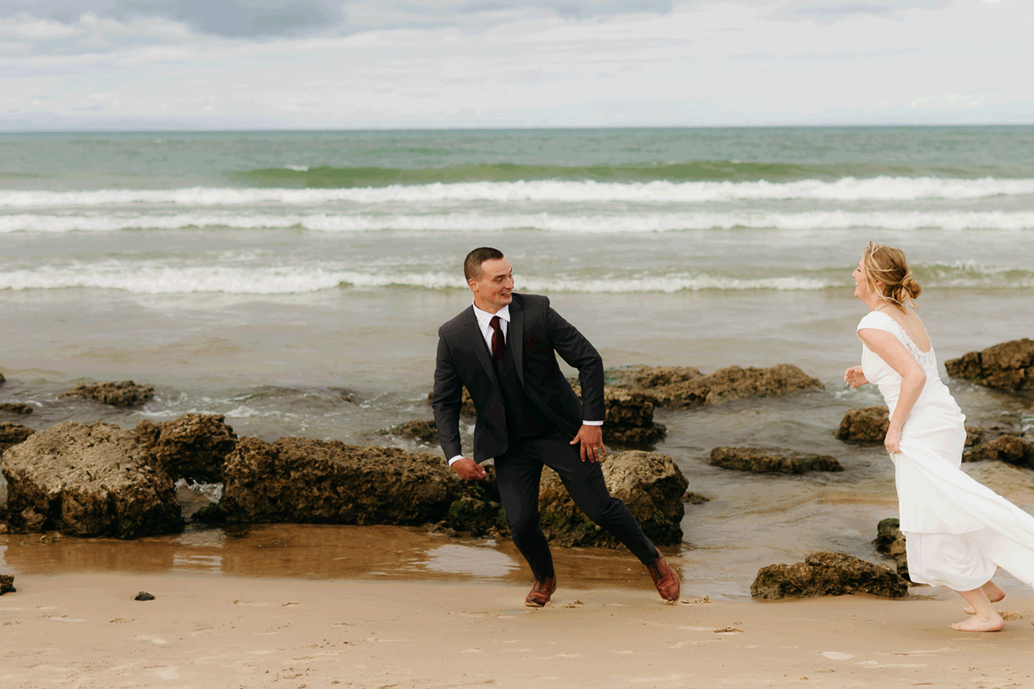 Bride and groom embrace and take couple portraits together along the beach of Lake Michigan during their Indiana Dunes National Park wedding.