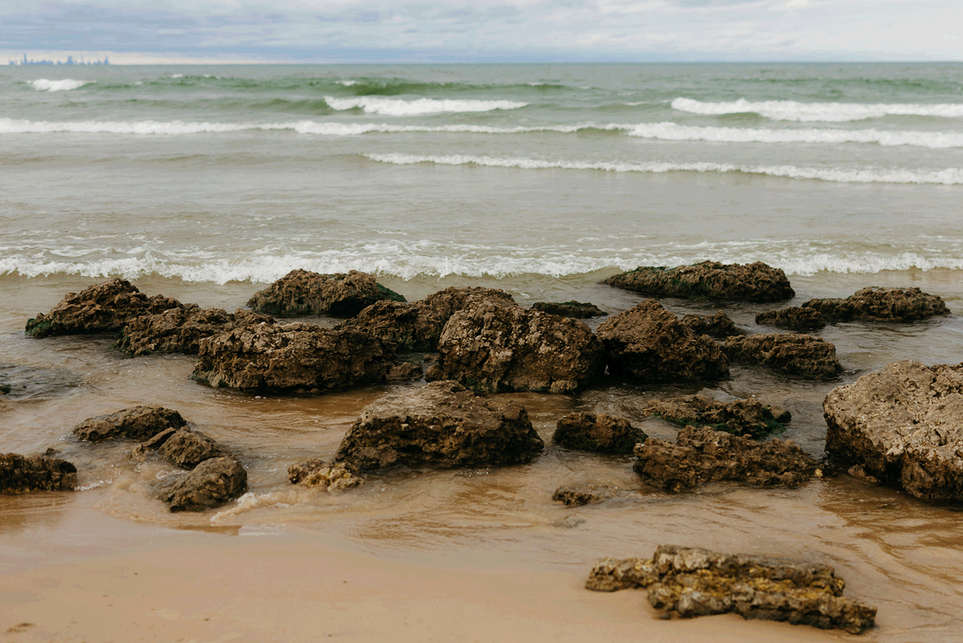 Bride and groom embrace and take couple portraits together along the beach of Lake Michigan during their Indiana Dunes National Park wedding.